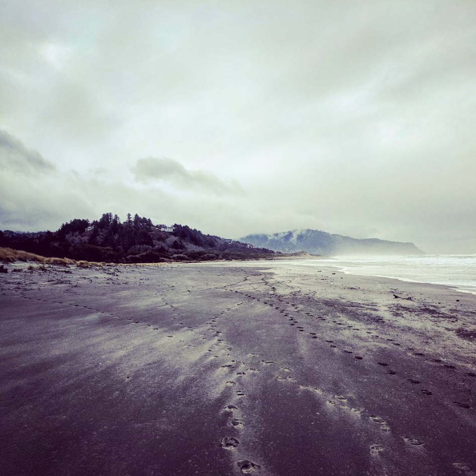 Windswept Oregon beach with footprints and wind patterns. 