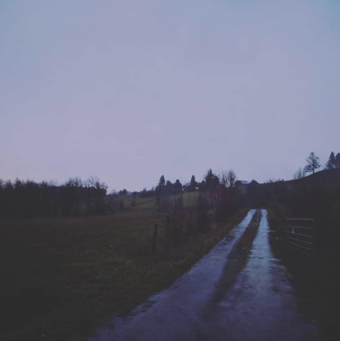 Rain-soaked gravel drive with purple sky and sodden fields all around.